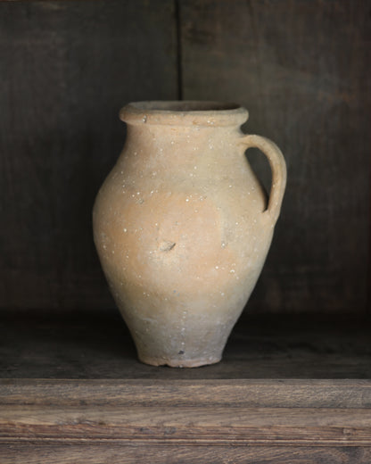 Vintage terracotta pot with a handle on a wooden surface