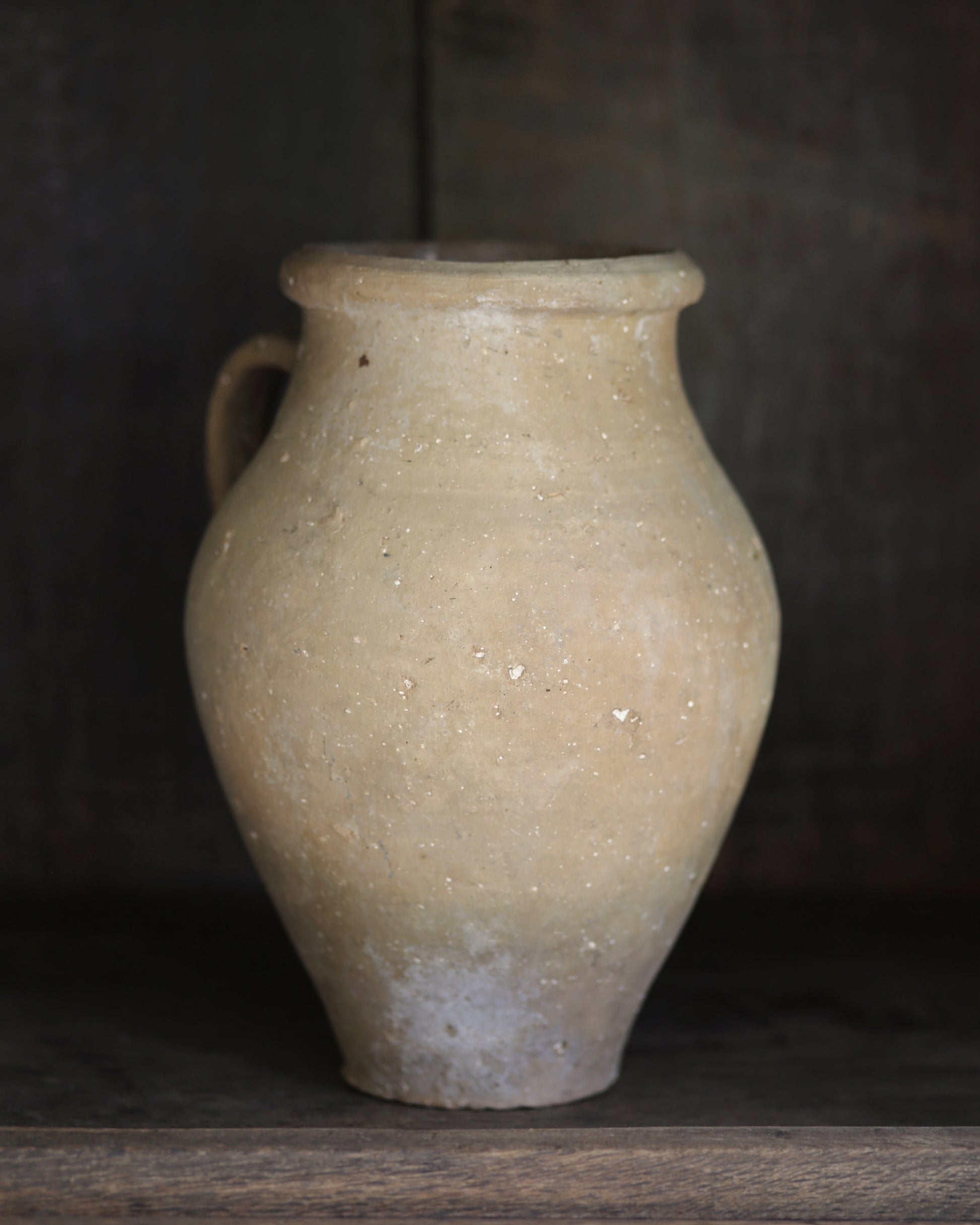 Natural sand toned pottery on a dark wooden surface with a dark background