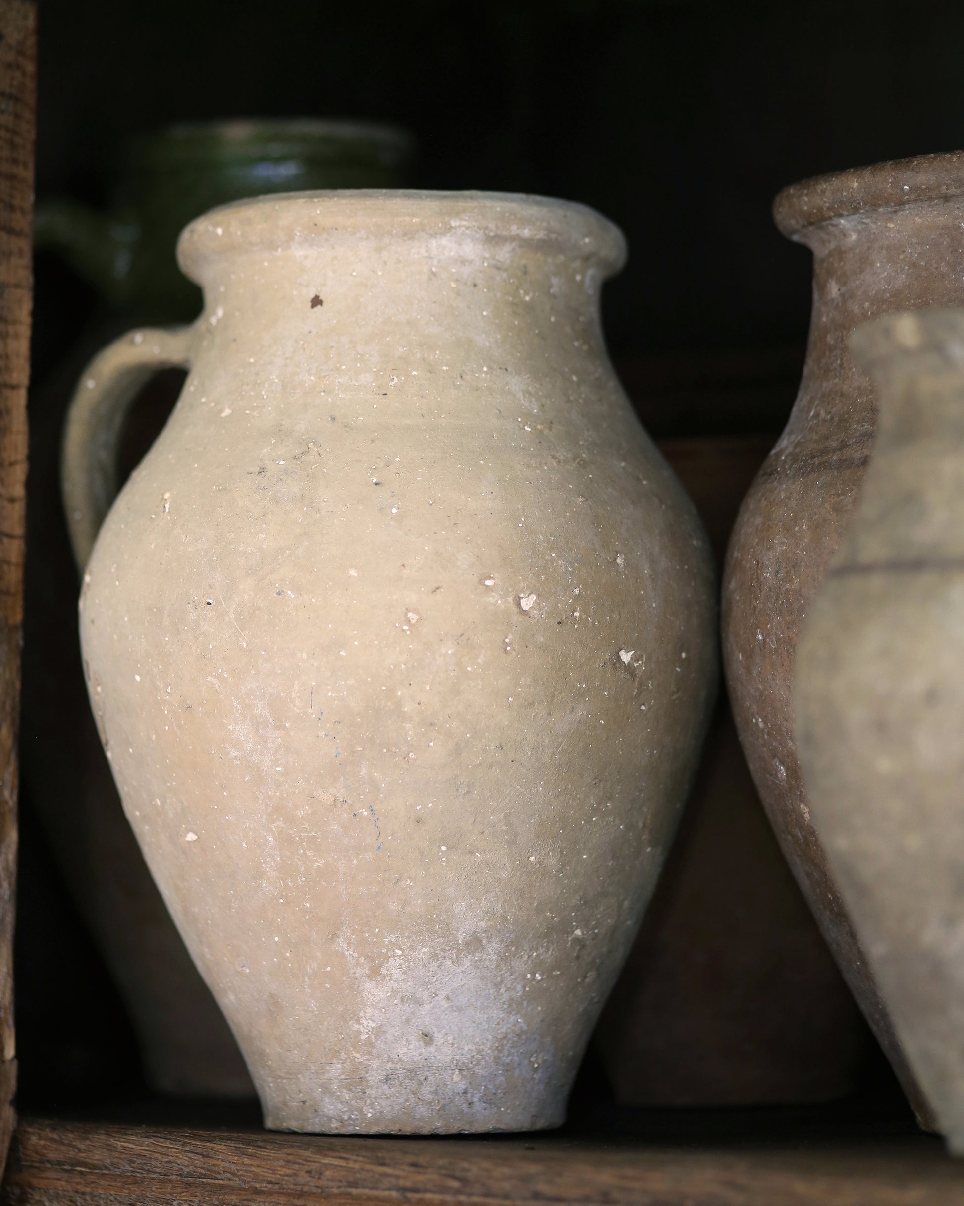 Two ceramic jars with a textured surface on a dark bookcase