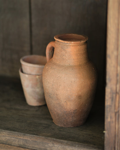 Vintage rustic clay pot with old terracotta plant pots on a wooden shelf