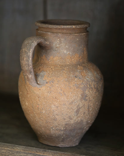 Brown ceramic pitcher pot with a handle on a dark background