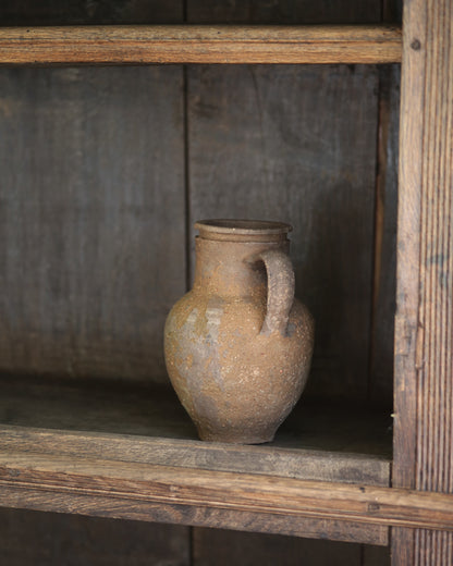 Vintage ceramic jar on a wooden shelf with a rustic background