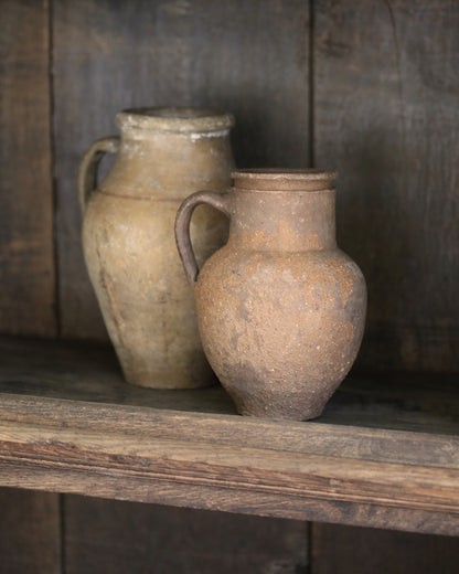 Two rustic clay pots on a wooden shelf with a dark wooden background