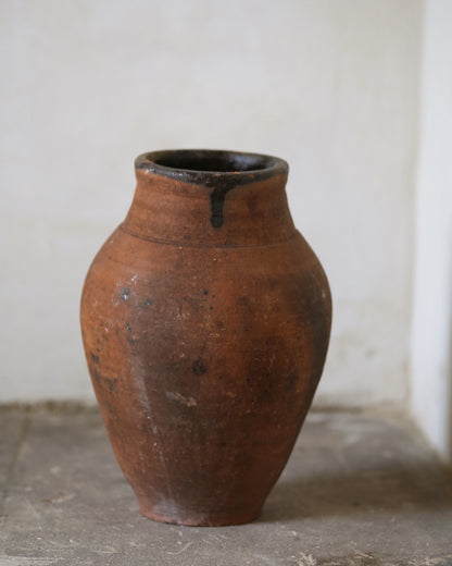 Brown ceramic vase on a gray surface with a white background