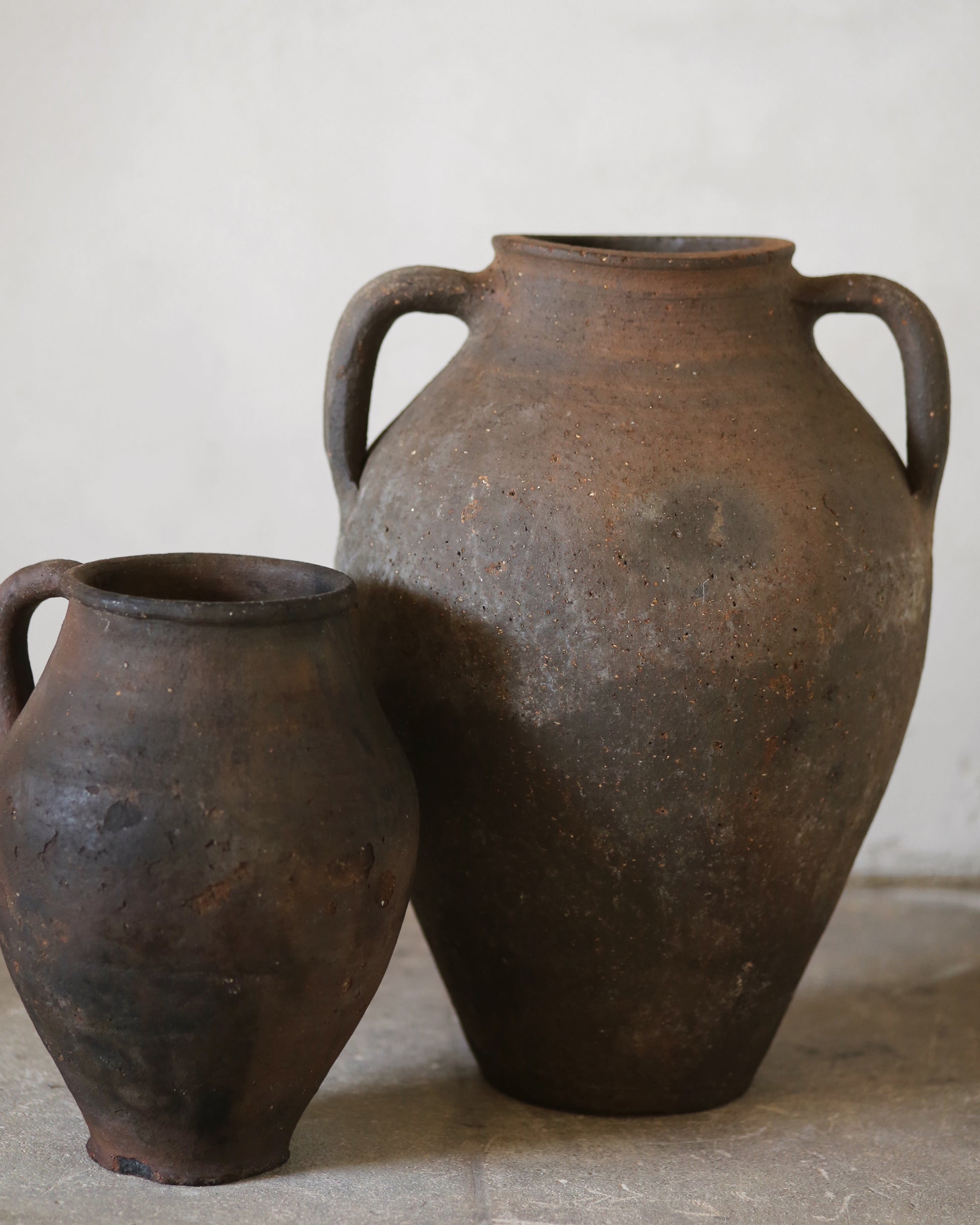 Two rustic antique clay pots on a neutral background