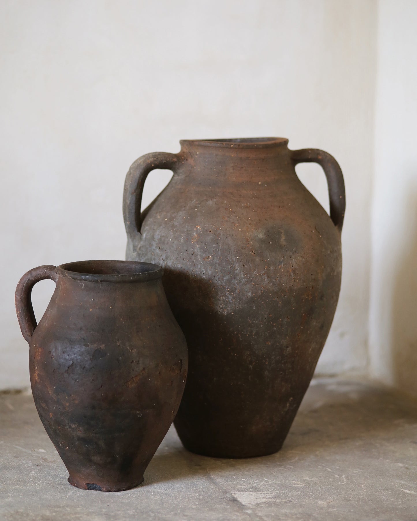 Two rustic clay pots on a wooden surface with a neutral background