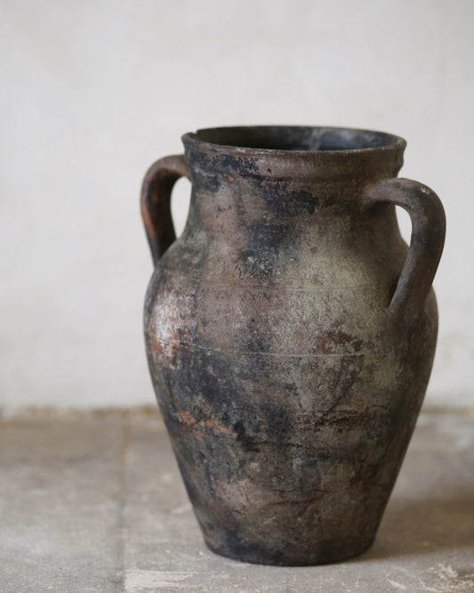 Vintage terracotta vase with two handles on a neutral background