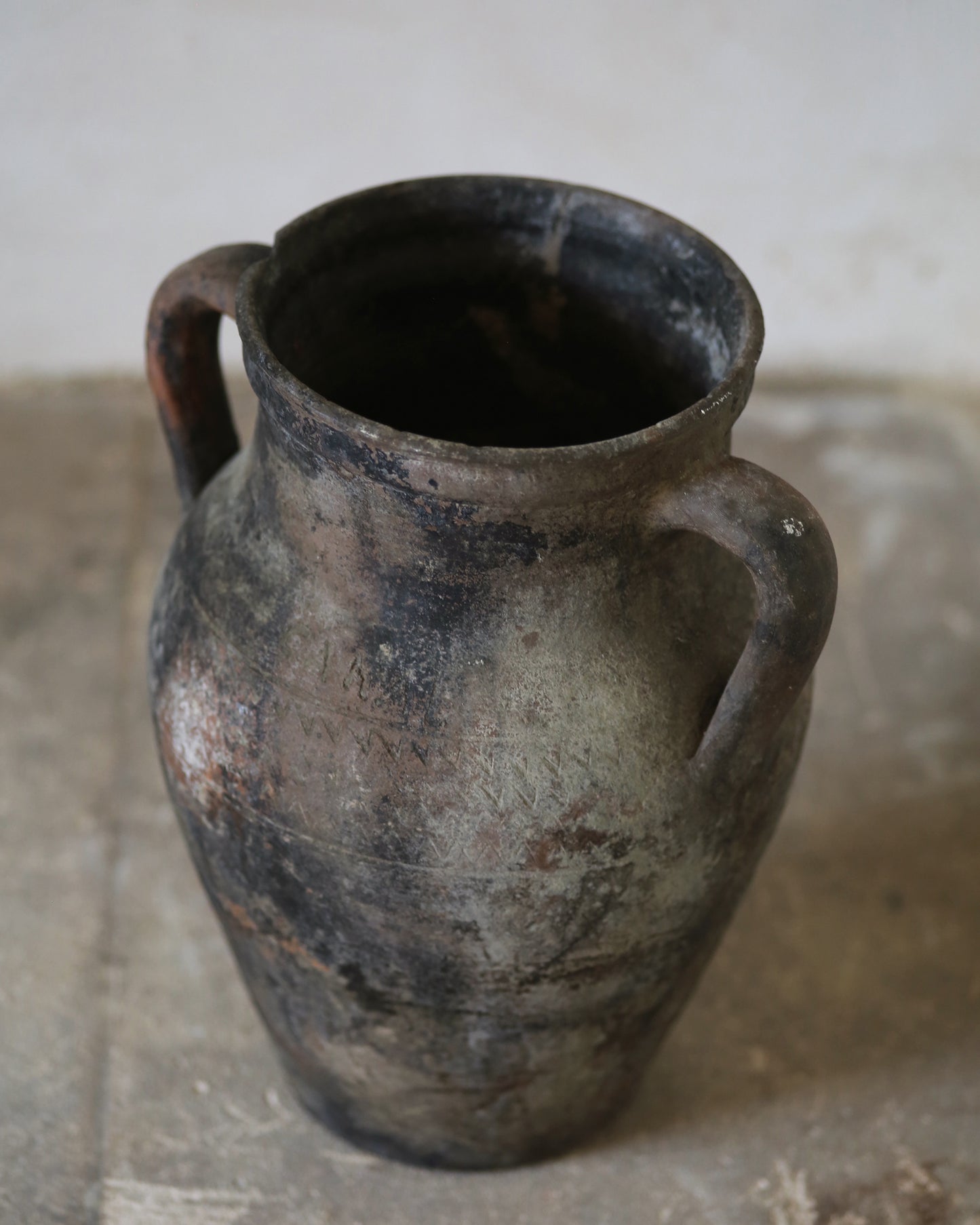 Aged patina on decorative antique terracotta vase sat on flagstone floor