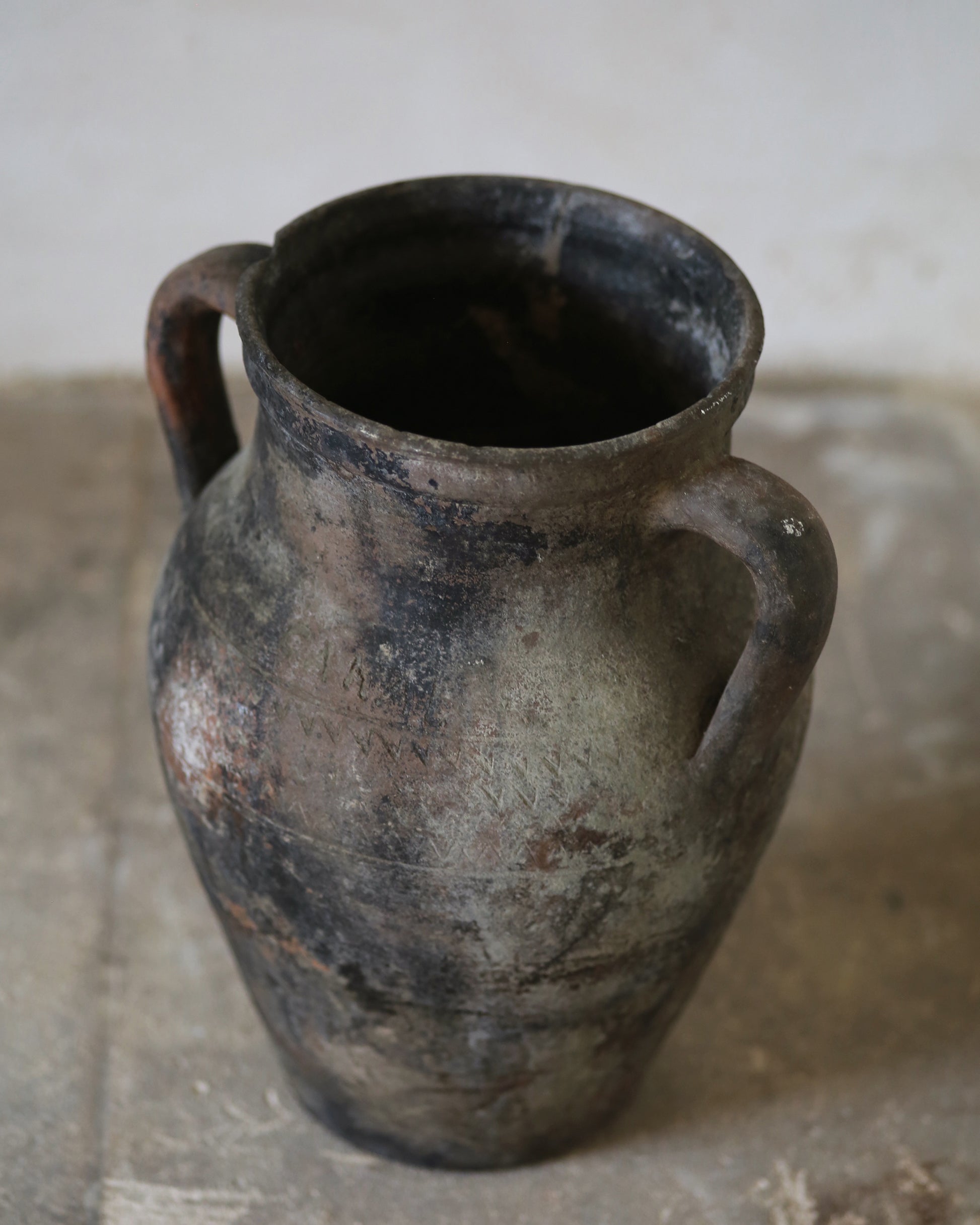 Aged patina on decorative antique terracotta vase sat on flagstone floor