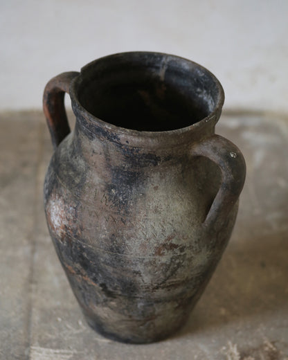 Aged patina on decorative antique terracotta vase sat on flagstone floor