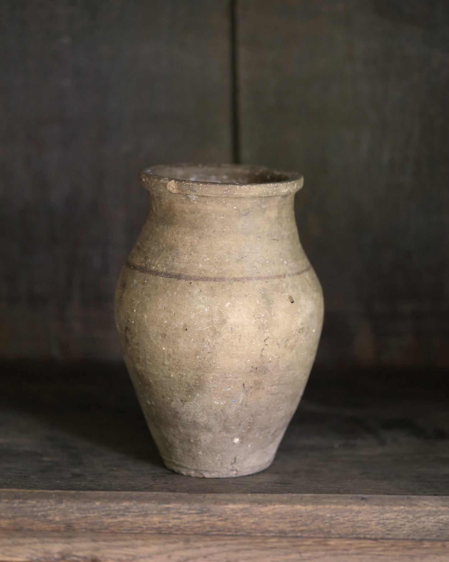Vintage neutral terracotta pot on a wooden surface with a dark background