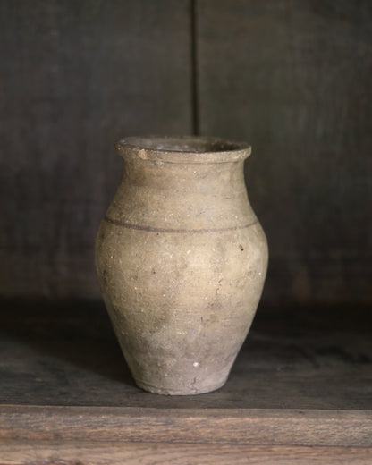 Vintage neutral terracotta pot on a wooden surface with a dark background