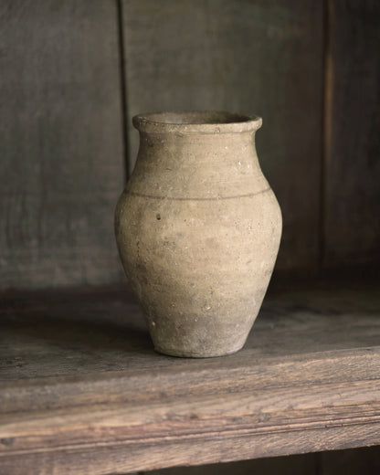 Pale vintage terracotta pot sat in a wooden bookcase