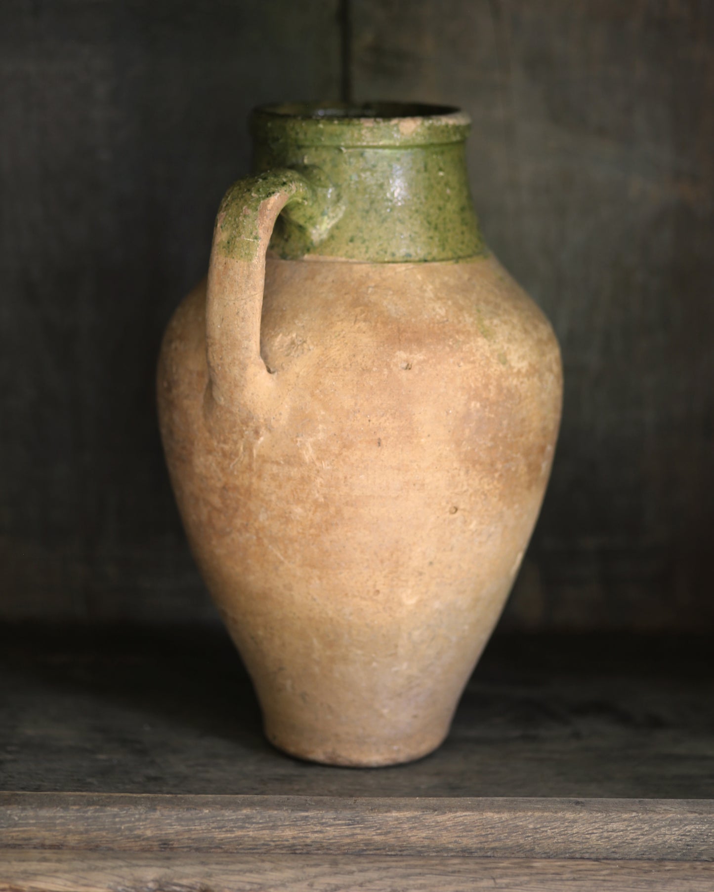 Vintage ceramic pitcher pot with green top on a wooden surface
