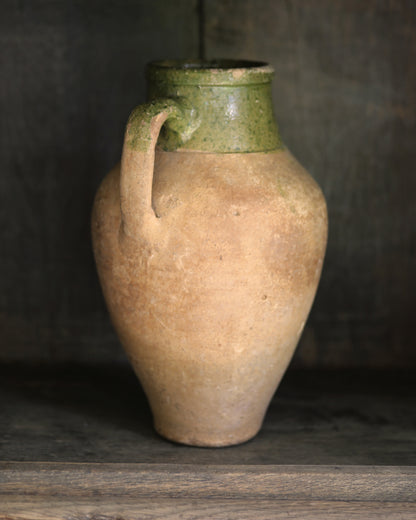 Vintage ceramic pitcher pot with green top on a wooden surface