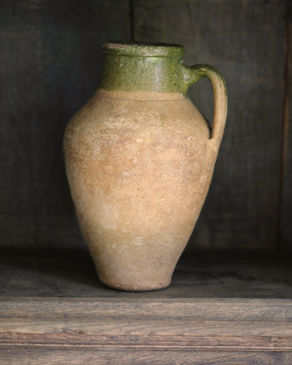 Vintage ceramic pitcher with green top on a wooden surface