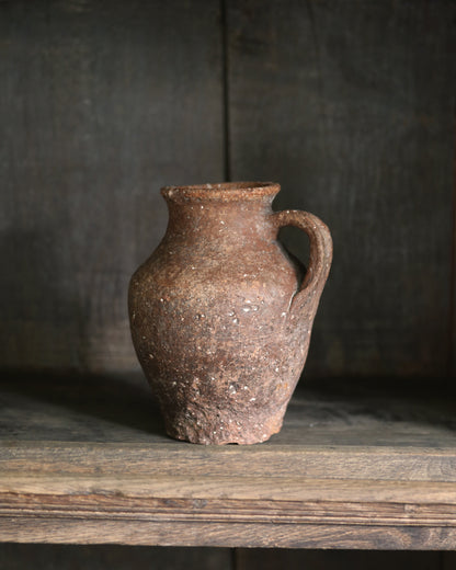 Natural terracotta ceramic pitcher pot on a wooden bookcase