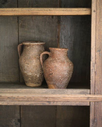 Two rustic antique clay pots on an antique elm wooden bookcase