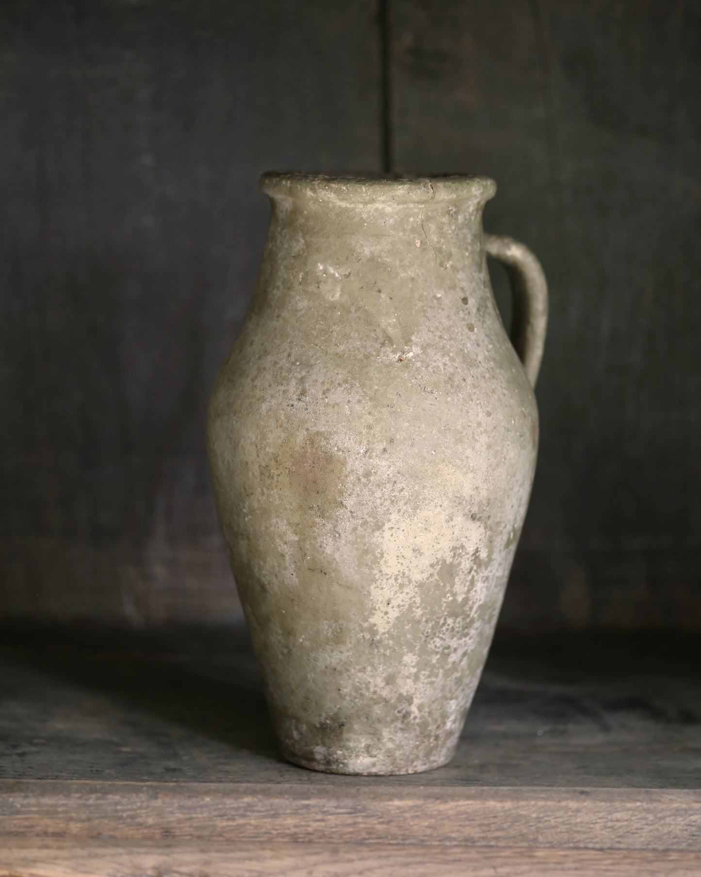 Vintage ceramic pitcher on a wooden surface with a dark background
