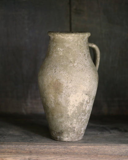Vintage ceramic pitcher on a wooden surface with a dark background