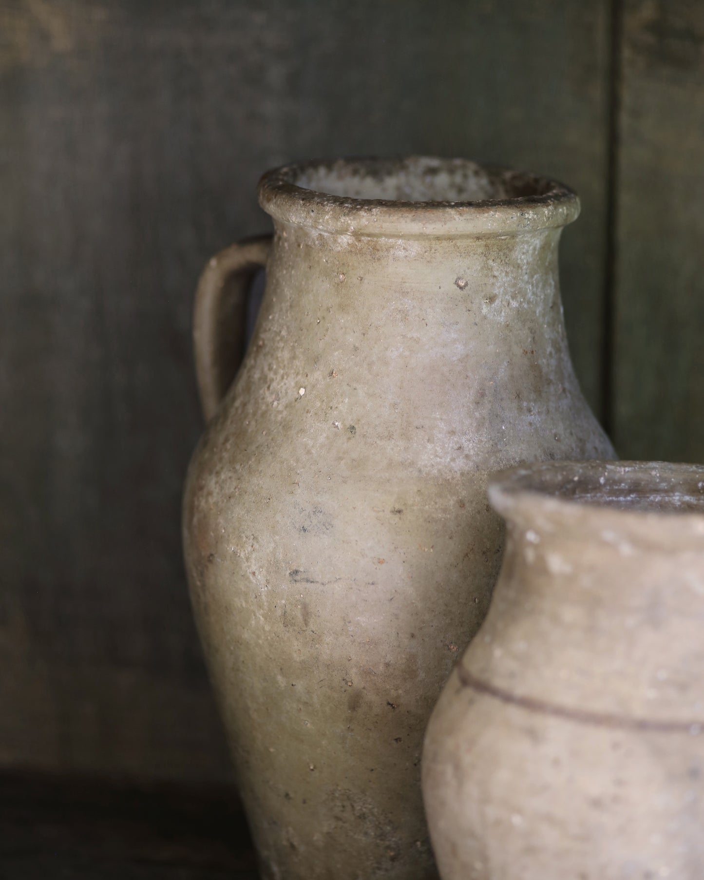 Two rustic textured antique clay pots with a blurred background
