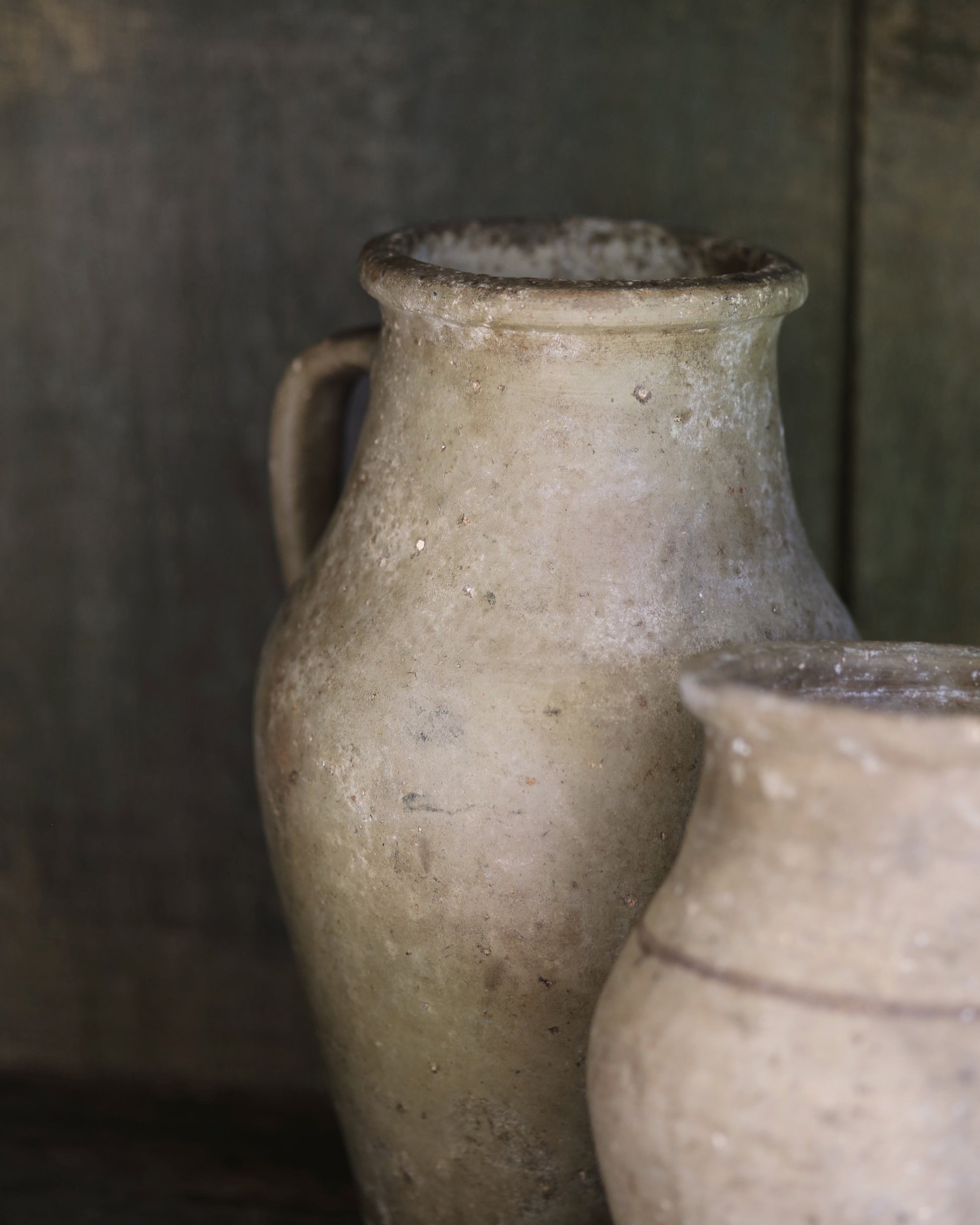 Two rustic textured antique clay pots with a blurred background