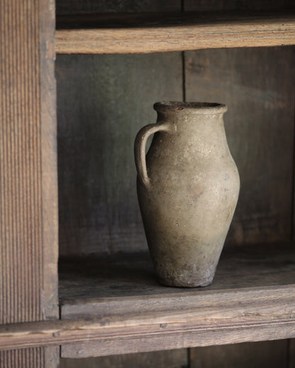 Vintage ceramic pitcher pot on an old rustic wooden bookcase