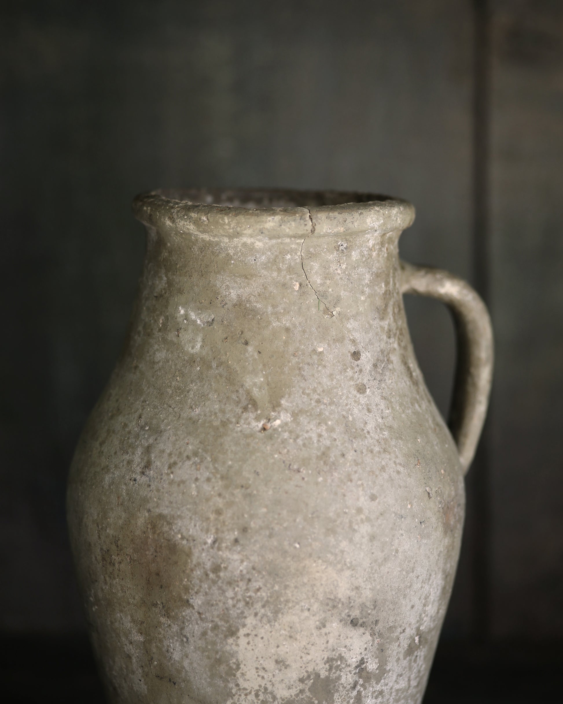 Close up of aged ceramic pitcher with a dark background