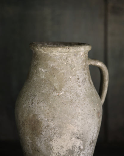 Close up of aged ceramic pitcher with a dark background