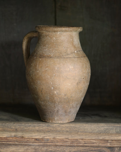 Vintage terracotta jar on a wooden surface with a dark background