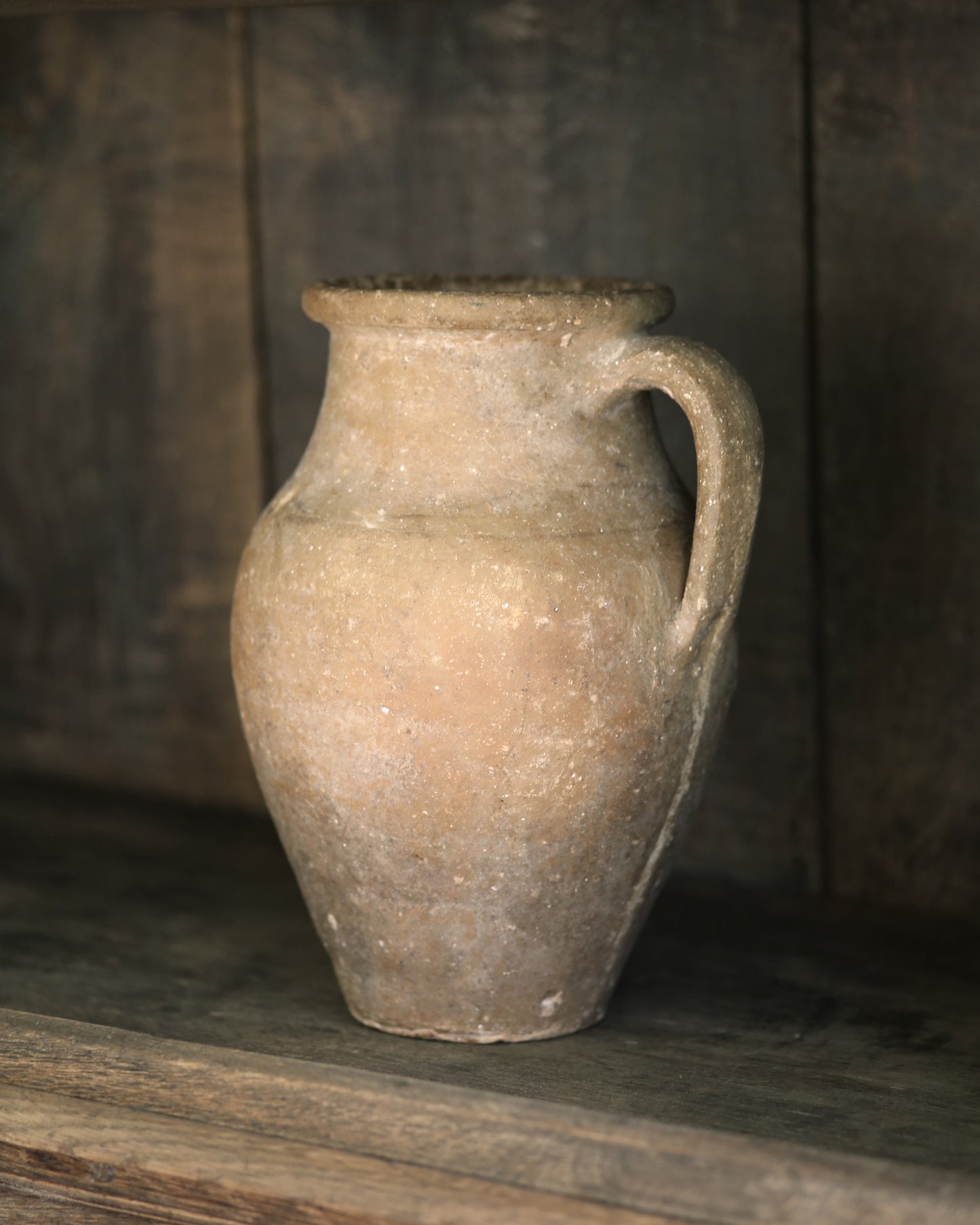 Terracotta pitcher on a wooden shelf bookcase