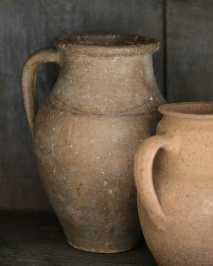 Two rustic clay pots with handles on a dark background