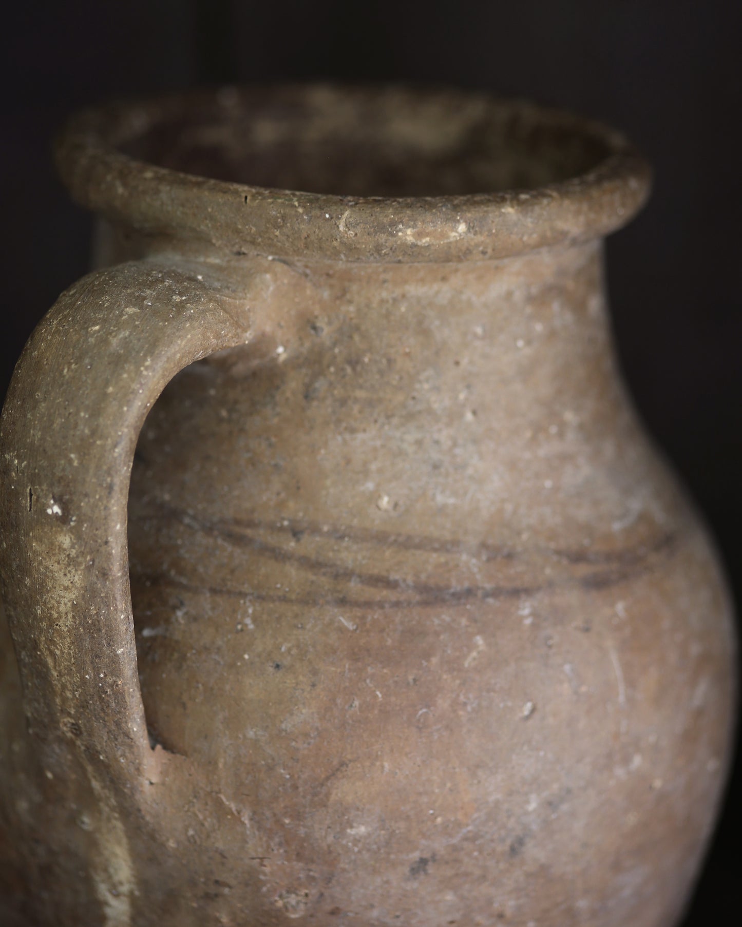 Brown ceramic pitcher jug with a handle on a dark background