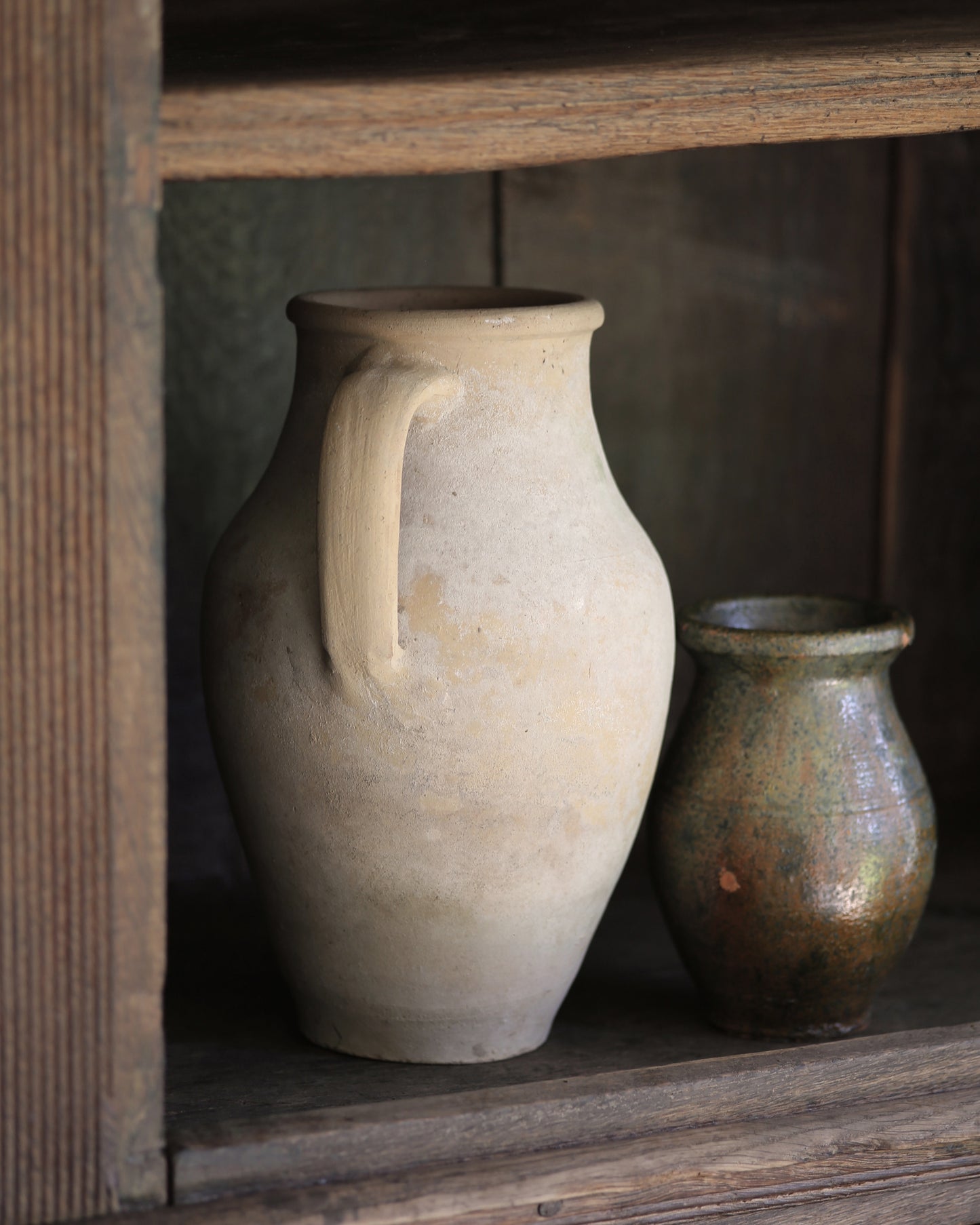 Two ceramic jars on a dark wooden bookcase