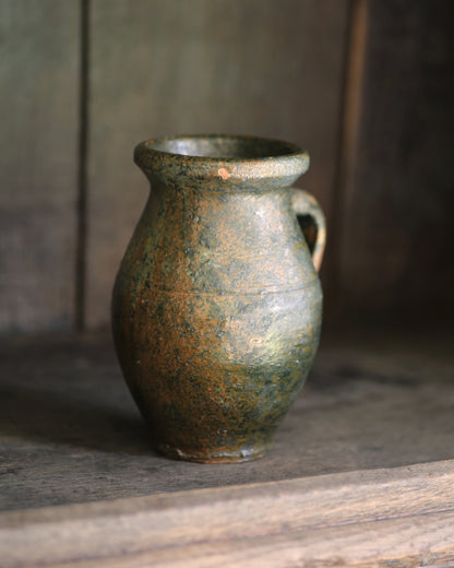 Green ceramic vase on a wooden surface with a dark background