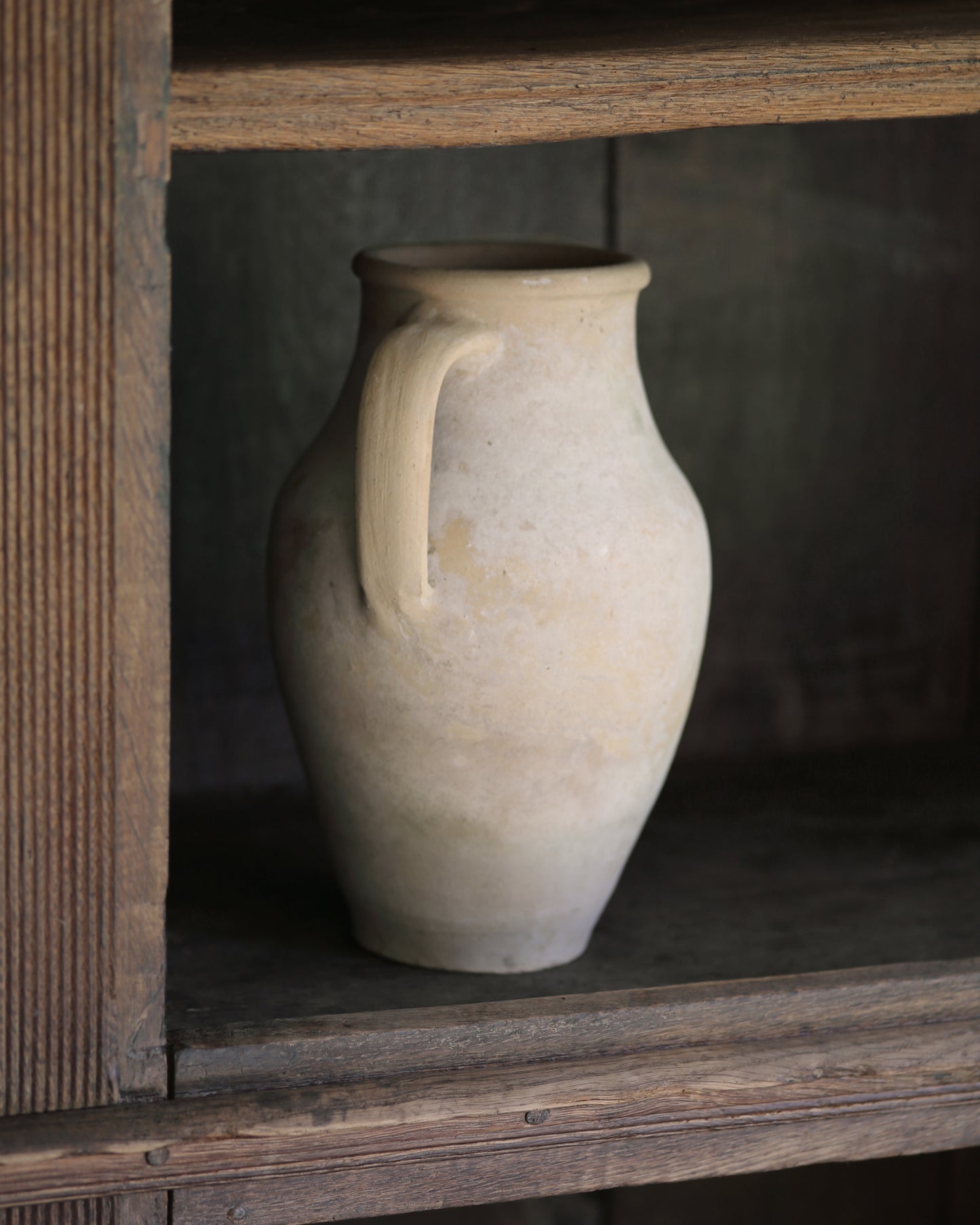 Whitewash pale terracotta pitcher pot on a wooden bookcase