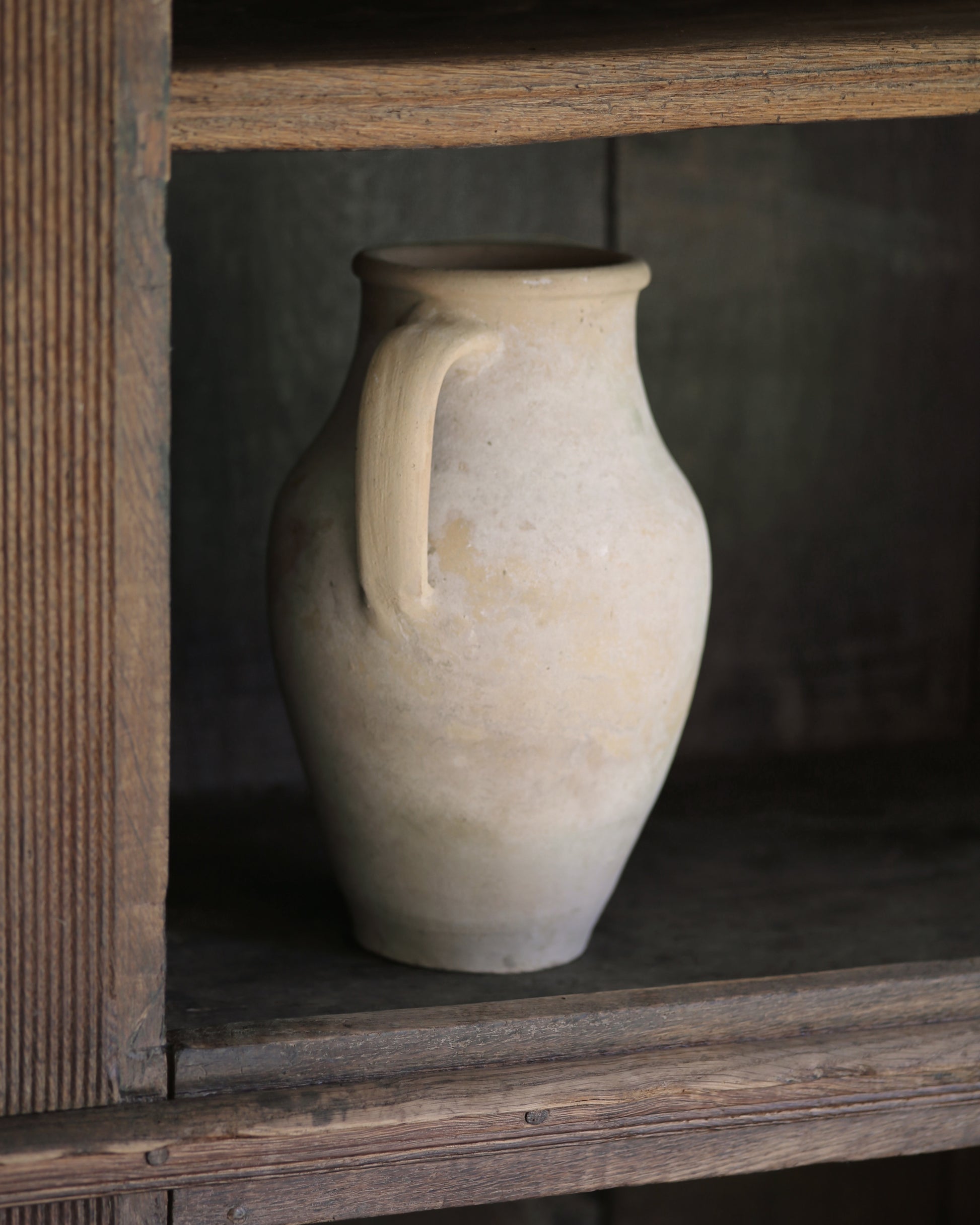 Whitewash pale terracotta pitcher pot on a wooden bookcase