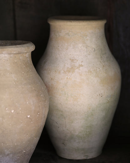 Two beige ceramic pots with rustic textured finish on a dark background