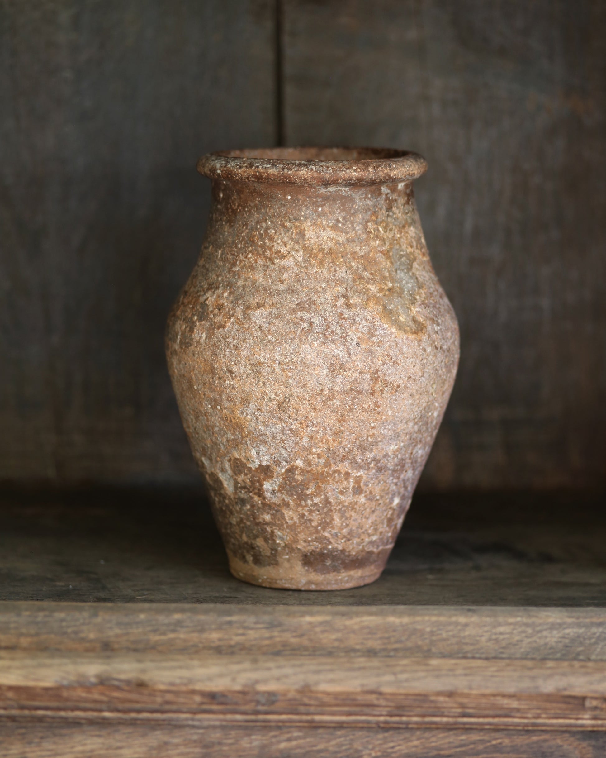 Vintage brown terracotta vase on a wooden surface with a blurred background