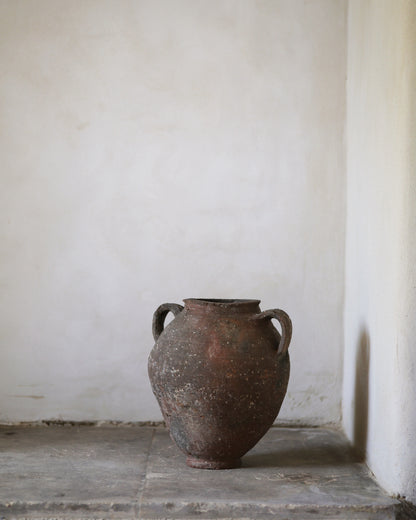 Vintage terracotta pottery on a stone surface with a white wall background
