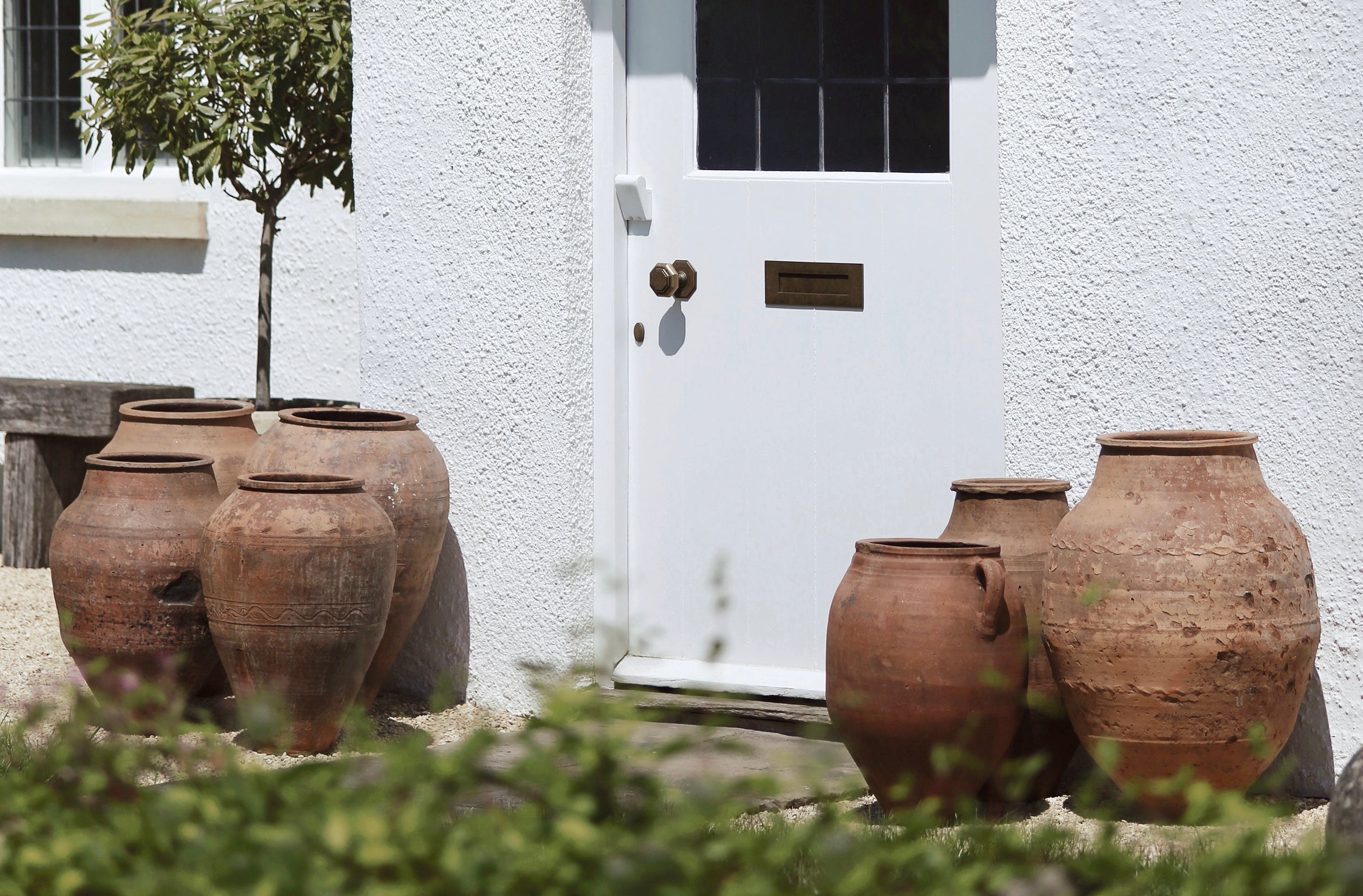 Collection of seven rustic textured terracotta garden pots in traditional Turkish olive jar shapes