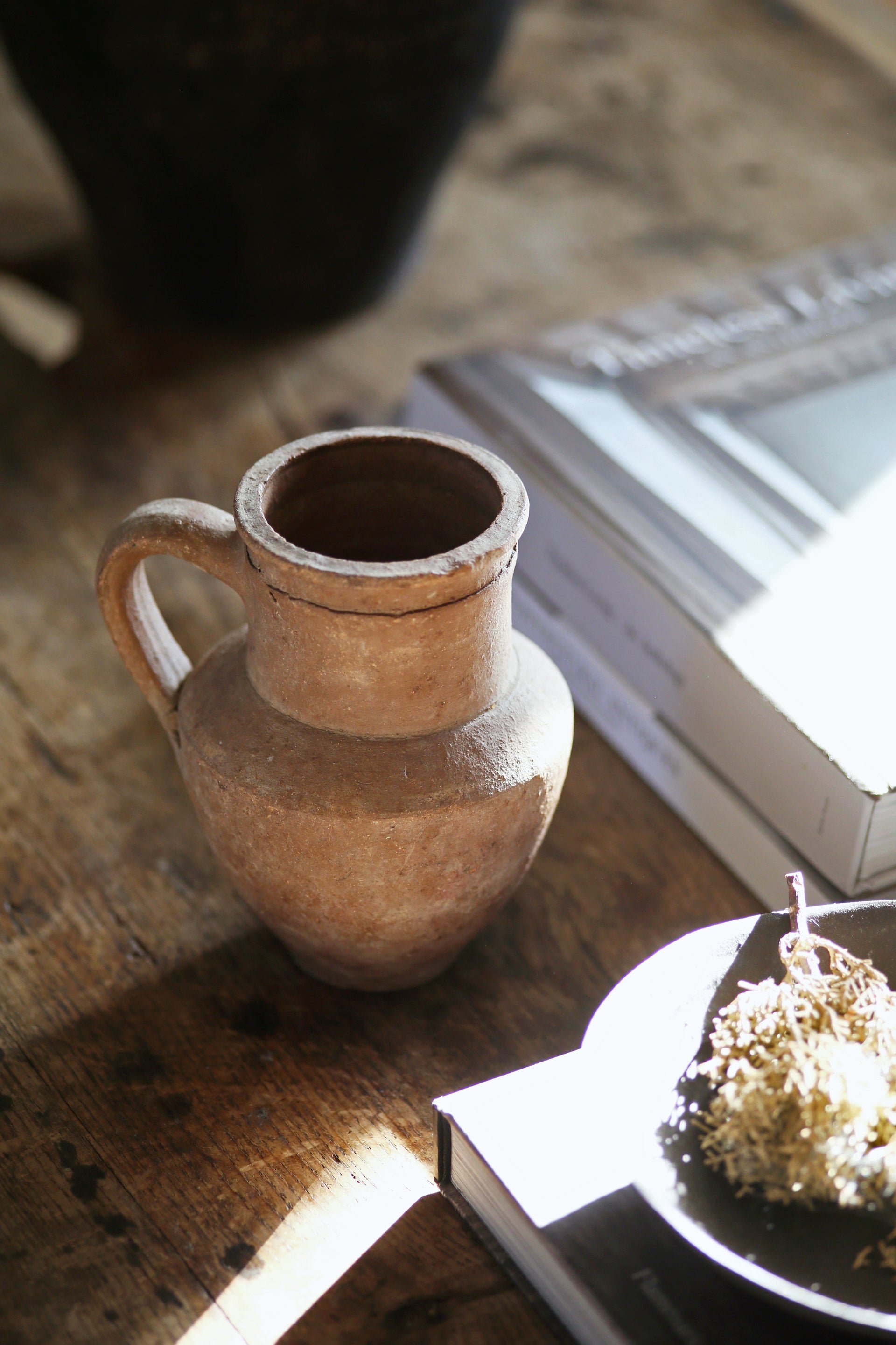 Antique terracotta pot styled on coffee table with other home accessories + coffee table books