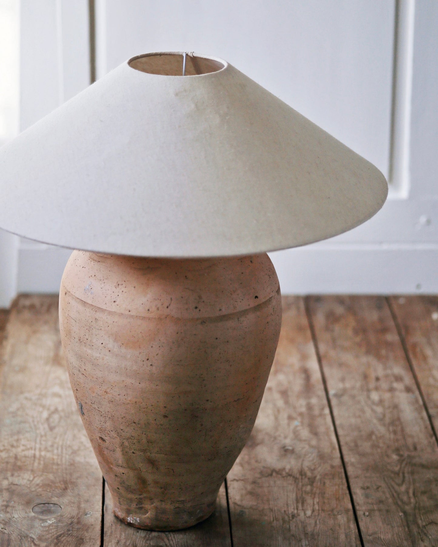 Antique clay urn table lamp base pictured with large linen shade