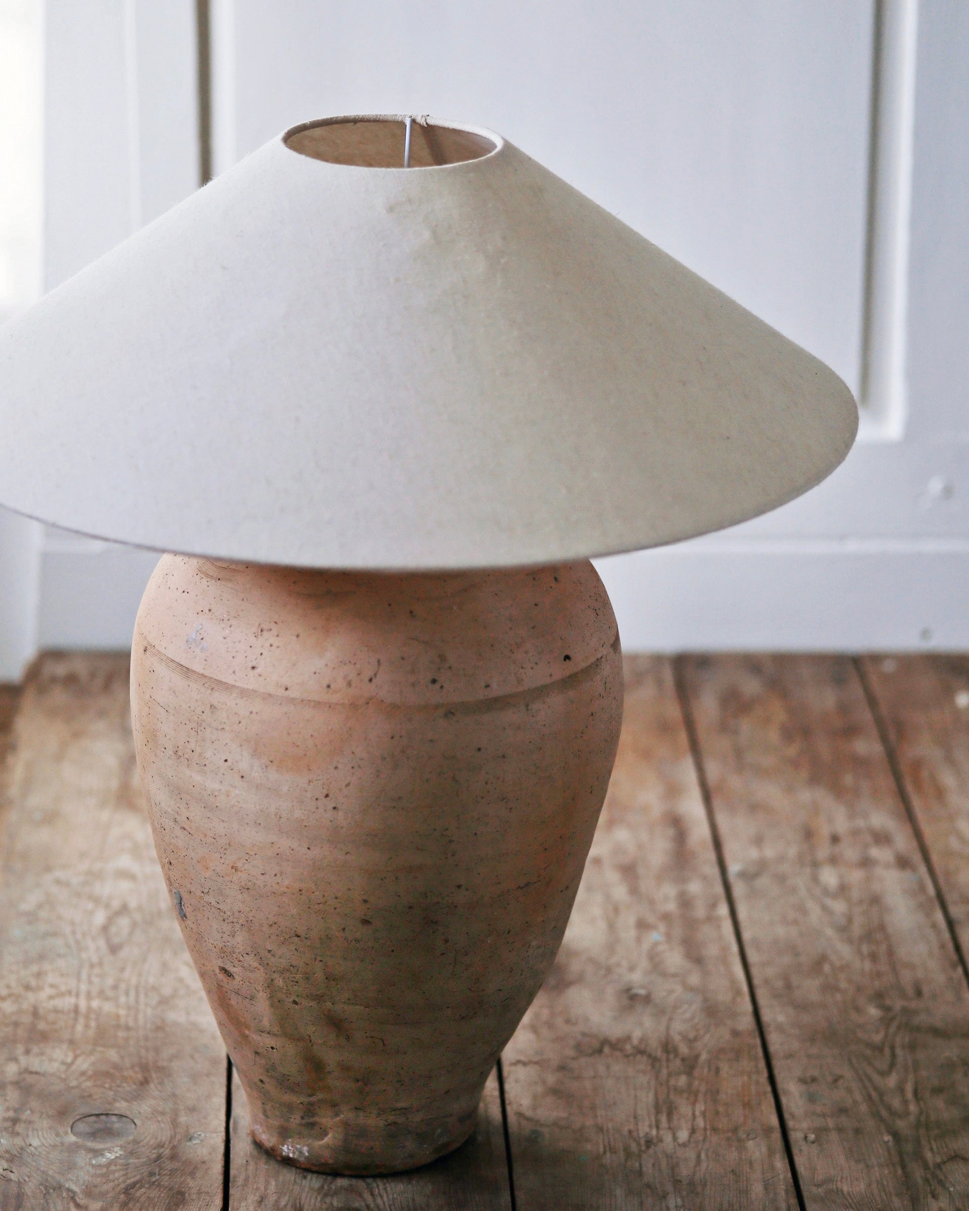 Antique clay urn table lamp base pictured with large linen shade