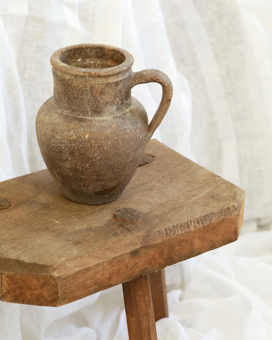 Terracotta pitcher pot sat on wooden stool