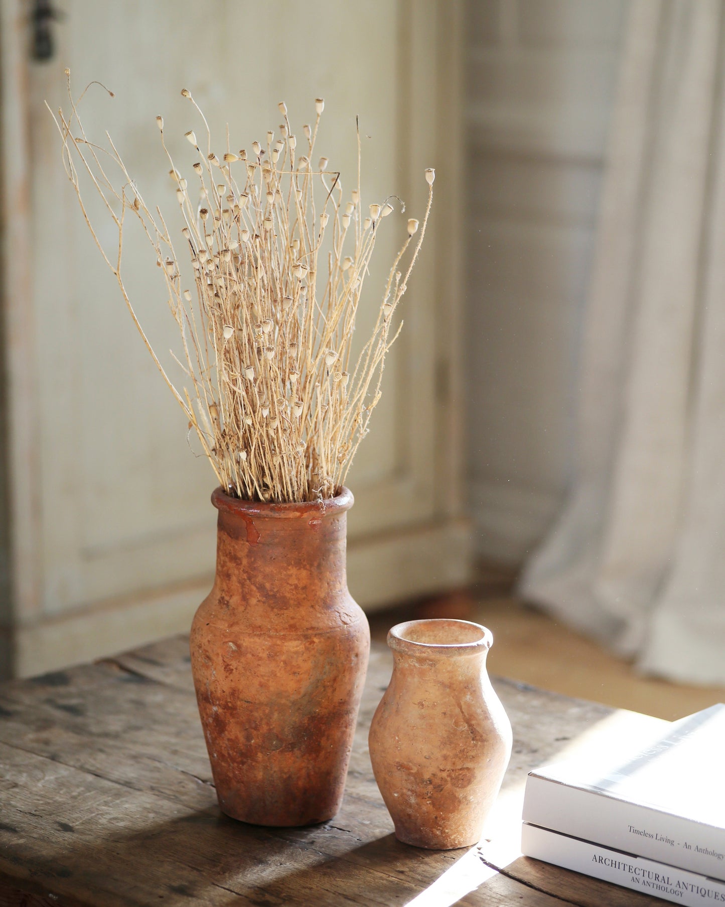 Antique terracotta toned vases on coffee table with dried flowers