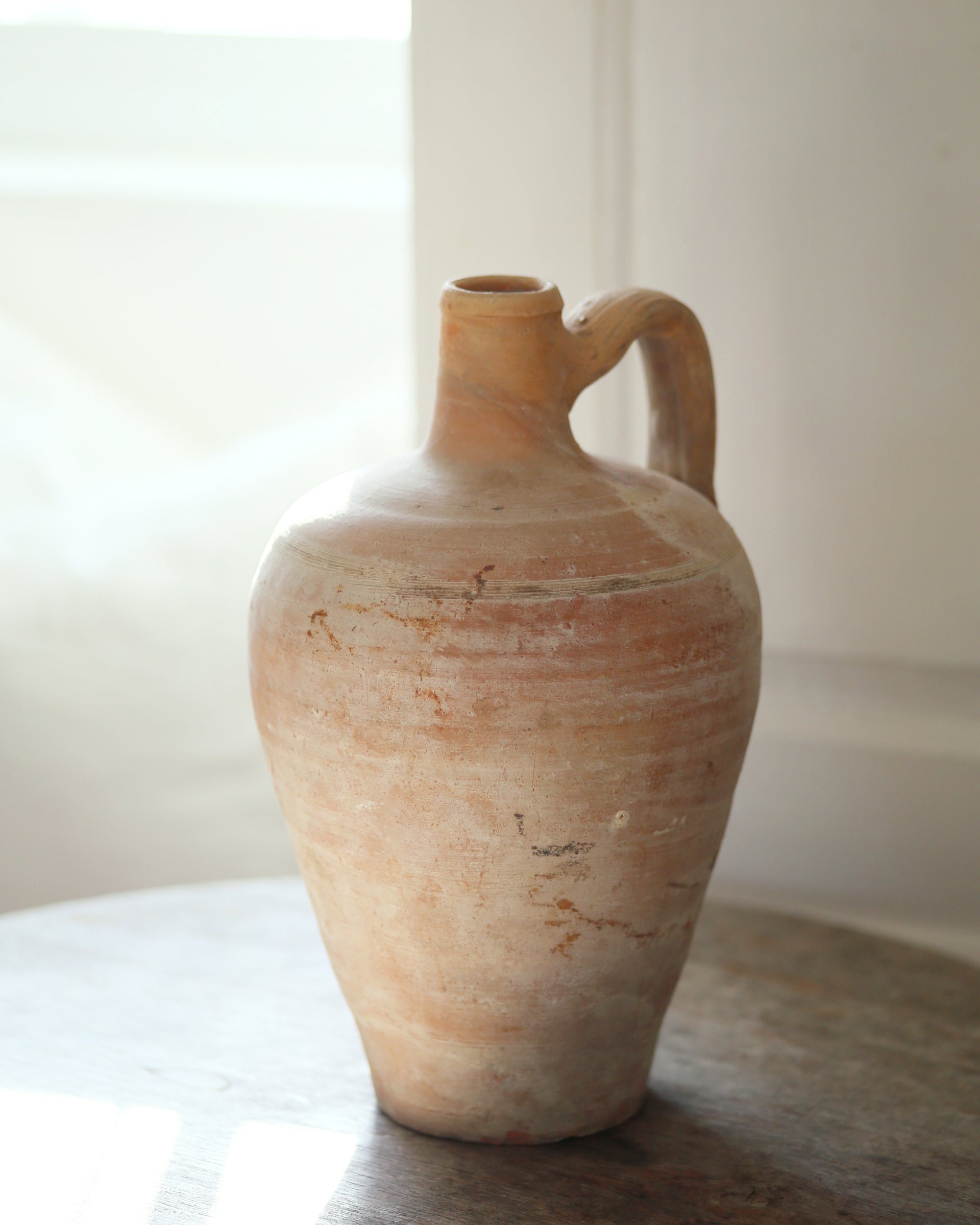 Naturally aged clay jug with bottle neck and handle