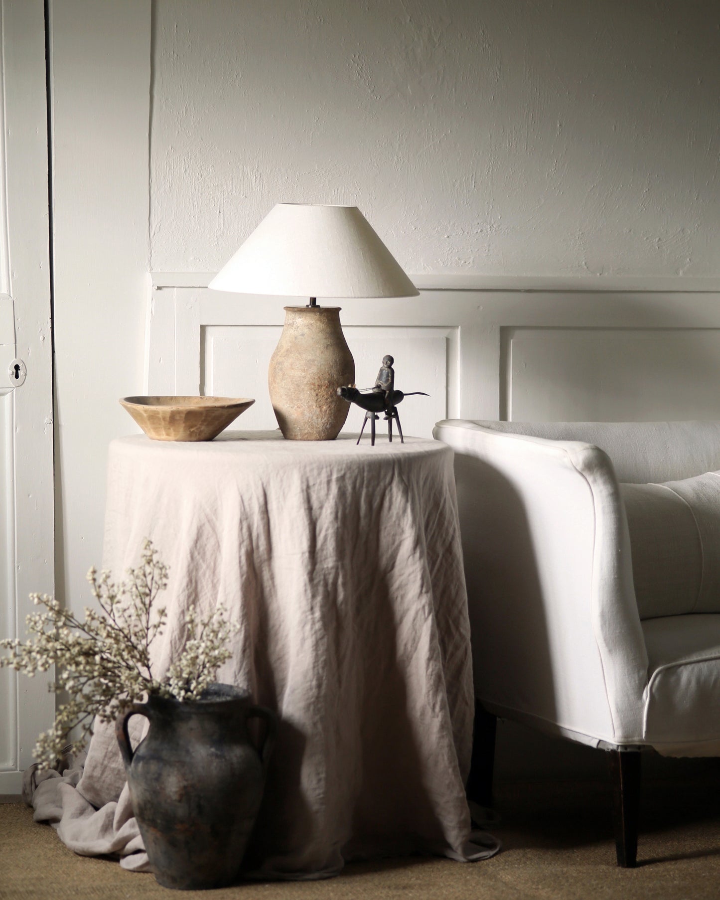 Antique table lamp with white linen shade in country home styled with antique accessories and furniture
