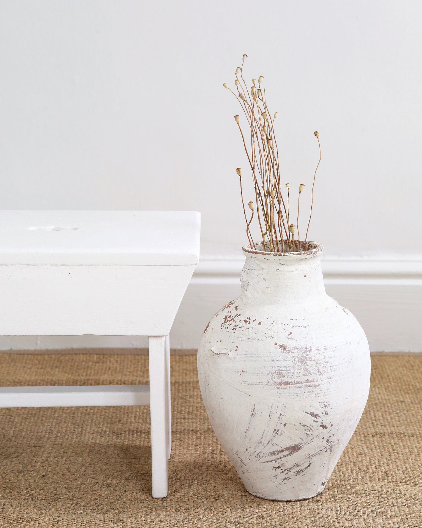 Side profile of milking stool shown alongside floor vase