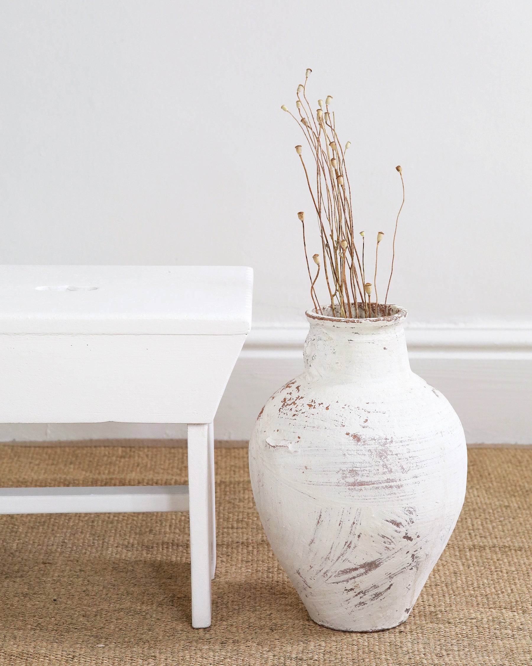 Side profile of milking stool shown alongside floor vase